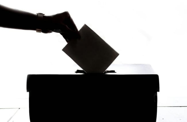 a person is casting a vote into a box