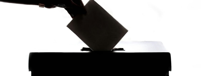 a person is casting a vote into a box